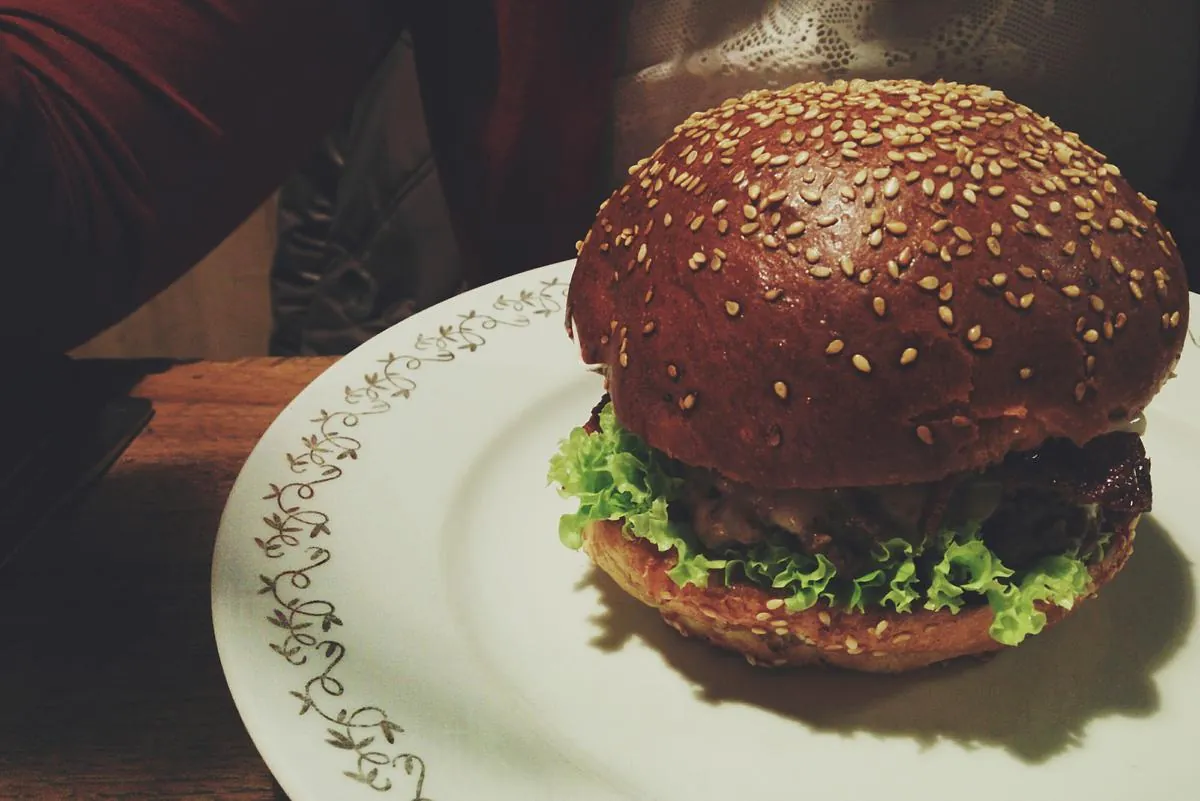 Hamburguesa artesanal servida en plato, con luz cálida